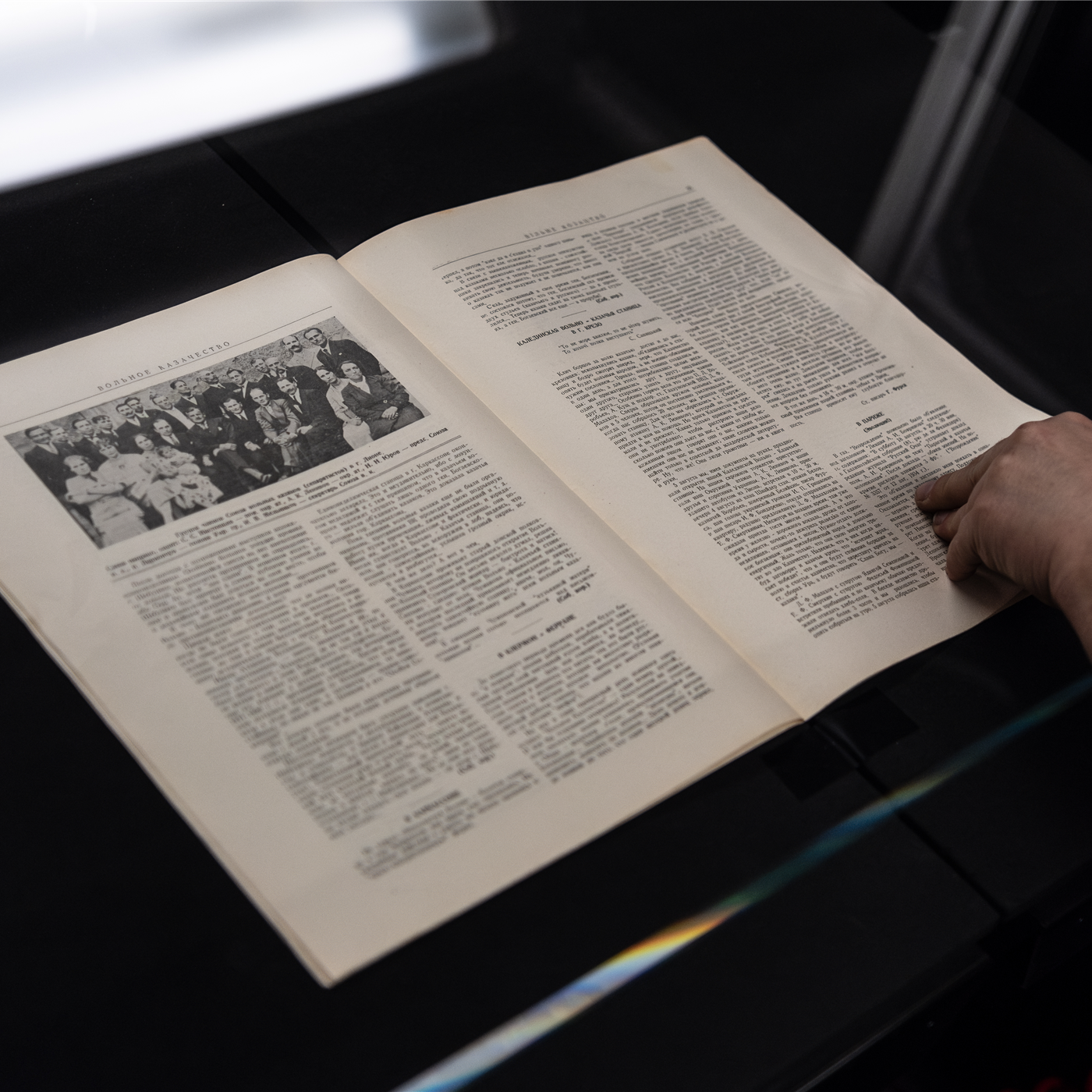 Человек оцифровывает открытую книгу на сканере; фотография иллюстрирует подготовку документов для локальной базы знаний